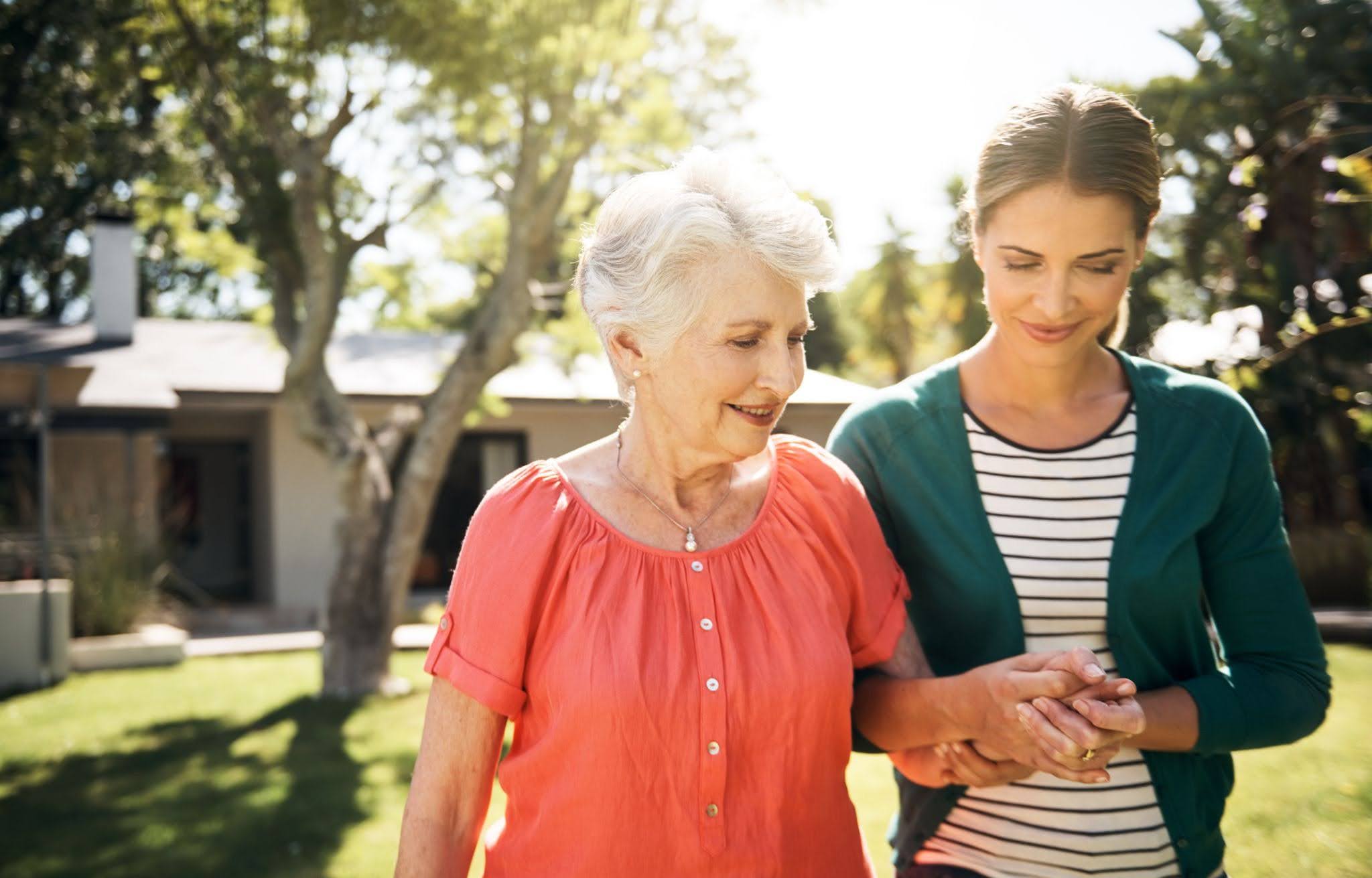An adult daughter helping her elderly mom while walking an talking about the 11 Signs It Might Be Time for Assisted Living in New Lenox, IL.